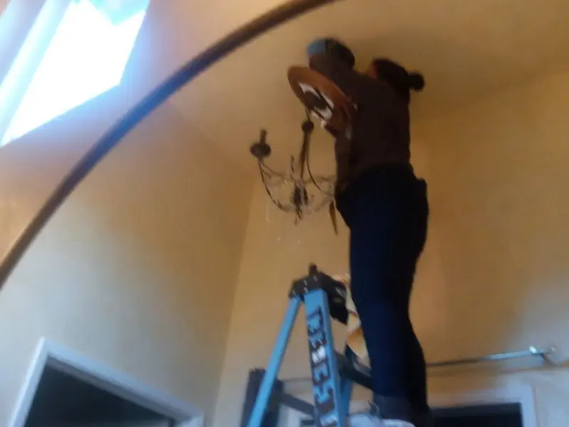 Electrician installing a chandelier in a Washington residence